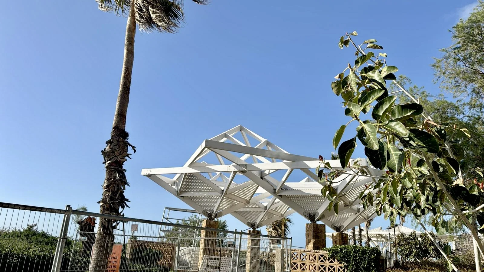 מבנה פרגולה לבנה מעץ במרחב פתוח